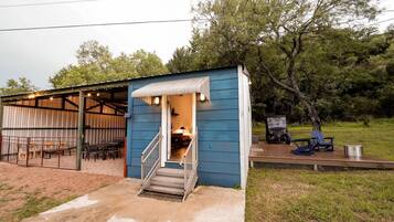 A small blue building with a covered outdoor seating area and a staircase leading to the entrance.