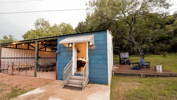 A small blue building with a covered outdoor seating area and a staircase leading to the entrance.