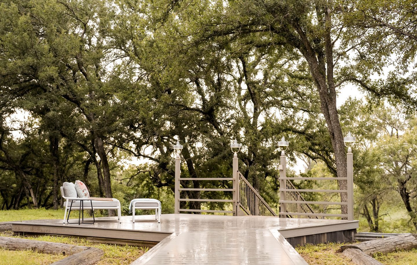 A wooden deck with a metal gate, surrounded by trees.