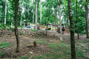 Un área boscosa con una hilera de cabañas coloridas, una escalera de madera y una mesa de picnic.