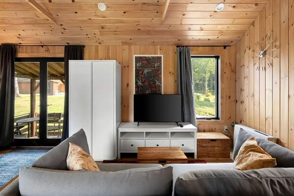 Ein Holzblockhaus-Interieur mit einer Couch, einem Fernseher und einem Stauraum.