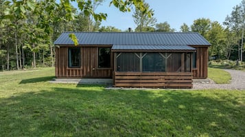 Eine Holzhütte mit Metalldach, großen Fenstern und einer Holzterrasse.