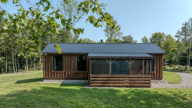 A wooden cabin with a metal roof, large windows, and a wooden deck. - Scandinavian-Style Cottage Fully Equipped in Vermont (Wolcott)