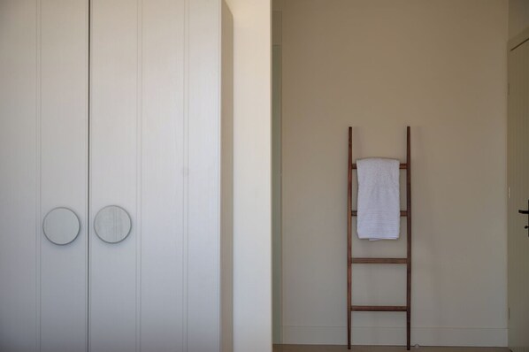 Ein schlichtes Badezimmer mit einem weißen Schrank, einer Holzleiter und einem Handtuch an der Wand.