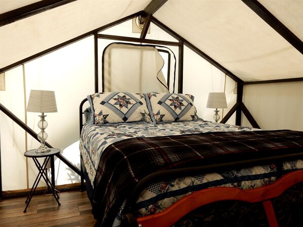Una habitación con carpa, una cama, dos lámparas y suelo de madera.