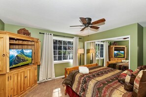 A bedroom with a large bed, a television, a ceiling fan, and a window with curtains. - Secluded Cabin with Breathtaking Lake Views and Foosball Table in Big Bear Lake, California (Big Bear Lake)