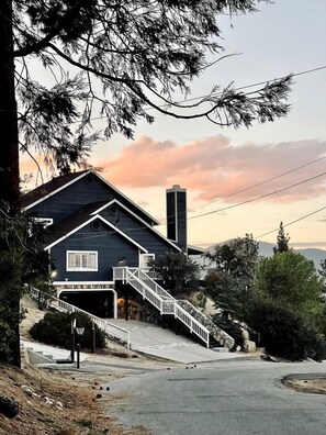 A two-story house with a garage, a staircase leading to the second floor, and a view of the surrounding landscape. - Secluded Cabin with Breathtaking Lake Views and Foosball Table in Big Bear Lake, California (Big Bear Lake)
