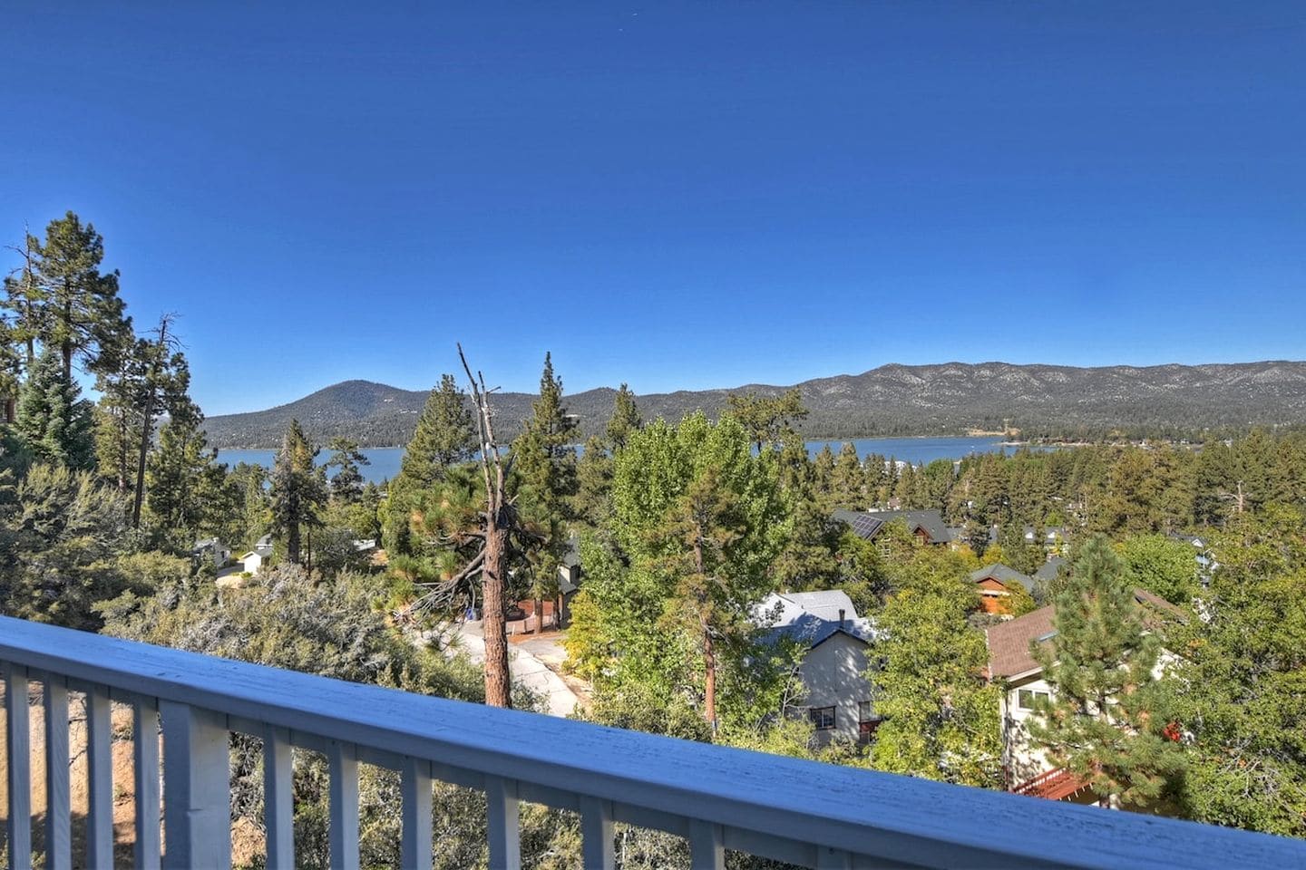 A residential area with a lake, mountains, and a clear sky.