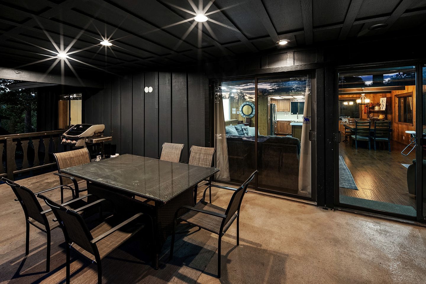 Een terras met een tafel, stoelen, een barbecue en uitzicht op het huis.