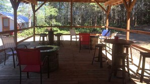 Eine Holzterrasse im Freien mit Sitzgelegenheiten und einem Feuerkorb.