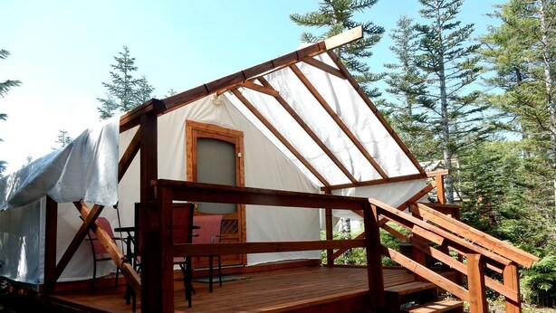 Eine Holzhütte mit überdachter Veranda, einem Stuhl und einem Fenster.