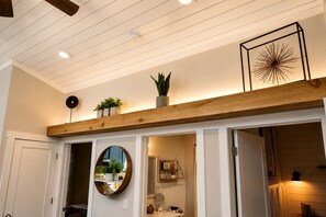 A room with a wooden beam ceiling, a round mirror, and a framed abstract art piece. - Exquisite Cabin with Stunning Interior, Outdoor Deck and Hot-Tub in Tennessee (Tracy City)