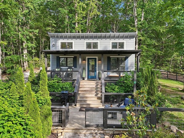 A two-story building with a central staircase, surrounded by greenery and a fenced area. - Exquisite Cabin with Stunning Interior, Outdoor Deck and Hot-Tub in Tennessee (Tracy City)