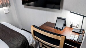 A compact hotel room with a bed, a desk with a computer, a TV mounted on the wall, and a desk lamp. - AMISTADHOTEL  ANNEXE (Matsuura)