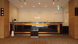 A reception desk with a sign reading "AMISTAD" and a clock above it. - AMISTADHOTEL  ANNEXE (Matsuura)