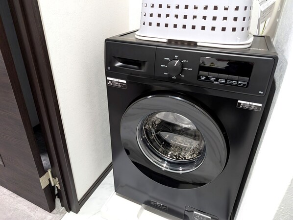 A black front-loading washing machine with a control panel, a basket on top, and a door with a latch.