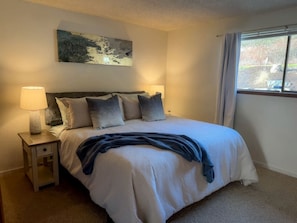 Une chambre à coucher avec un lit, des lampes de chevet, une fenêtre et un tableau au mur.