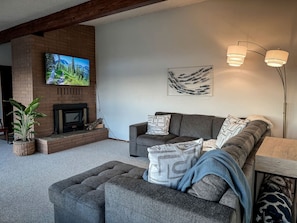 Una sala de estar con chimenea, un sofá, un televisor y una lámpara.