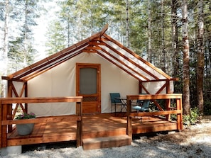 A wooden cabin with a porch, a door, and two chairs.