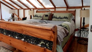 A bedroom with a wooden bed, a skylight, a small table, and a nightstand. - Idyllic Safari Tent for a Camping Getaway near Seattle, Washington (Belfair)