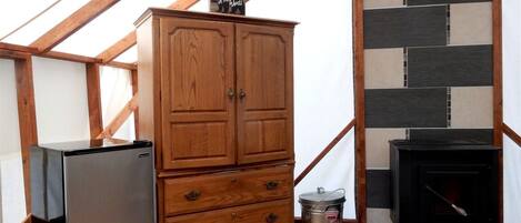 Un mueble de madera con cajones, una estufa negra y un refrigerador en una habitación con vigas de madera y un revestimiento de azulejos.