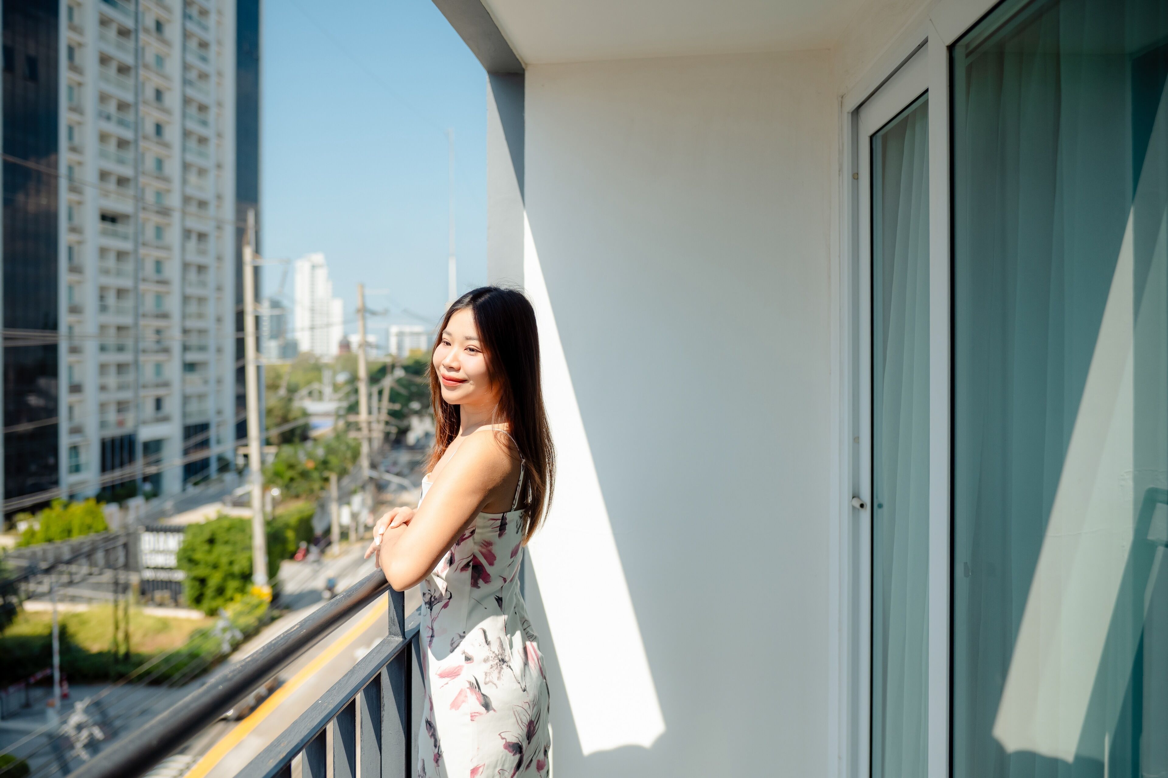 A balcony with a view of a cityscape, including high-rise buildings and a road.