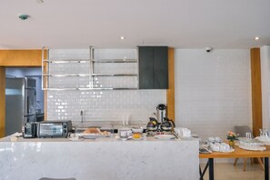 Een moderne keuken met een witte betegelde achterwand, roestvrijstalen apparatuur en een marmeren aanrecht.