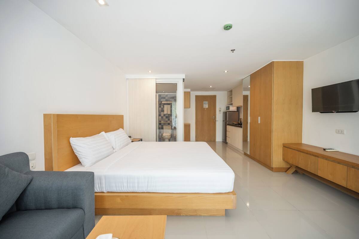 Une chambre d’hôtel moderne équipée d’un grand lit, d’un canapé, d’une télévision et d’une kitchenette.