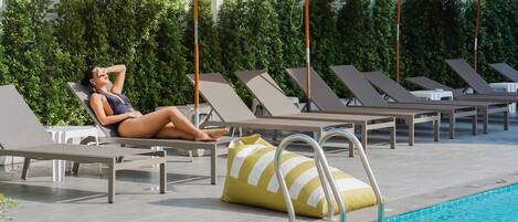 A poolside area with lounge chairs, umbrellas, and a pool.