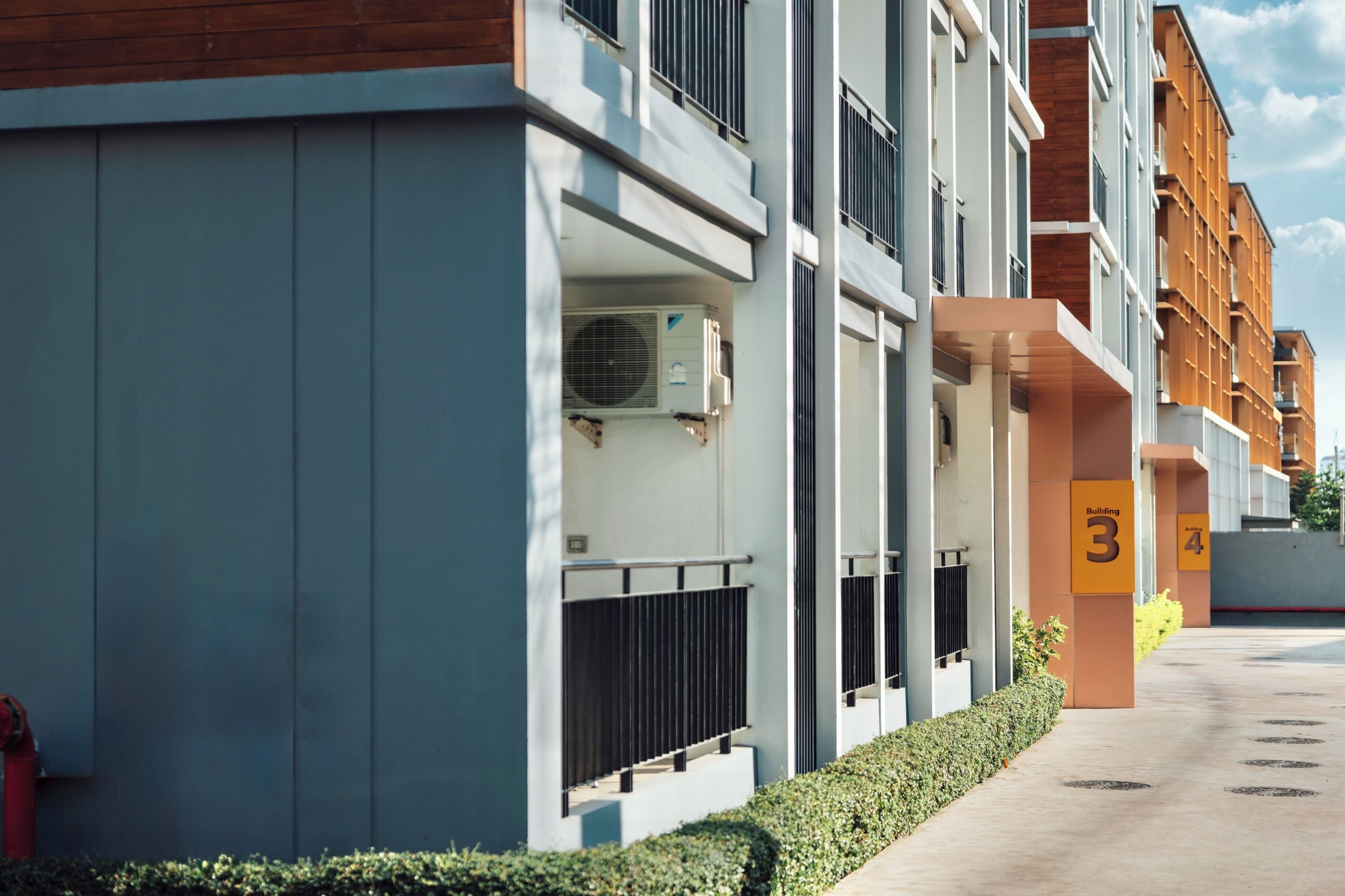 A modern building with numbered balconies, a fire hydrant, and a clear sky.