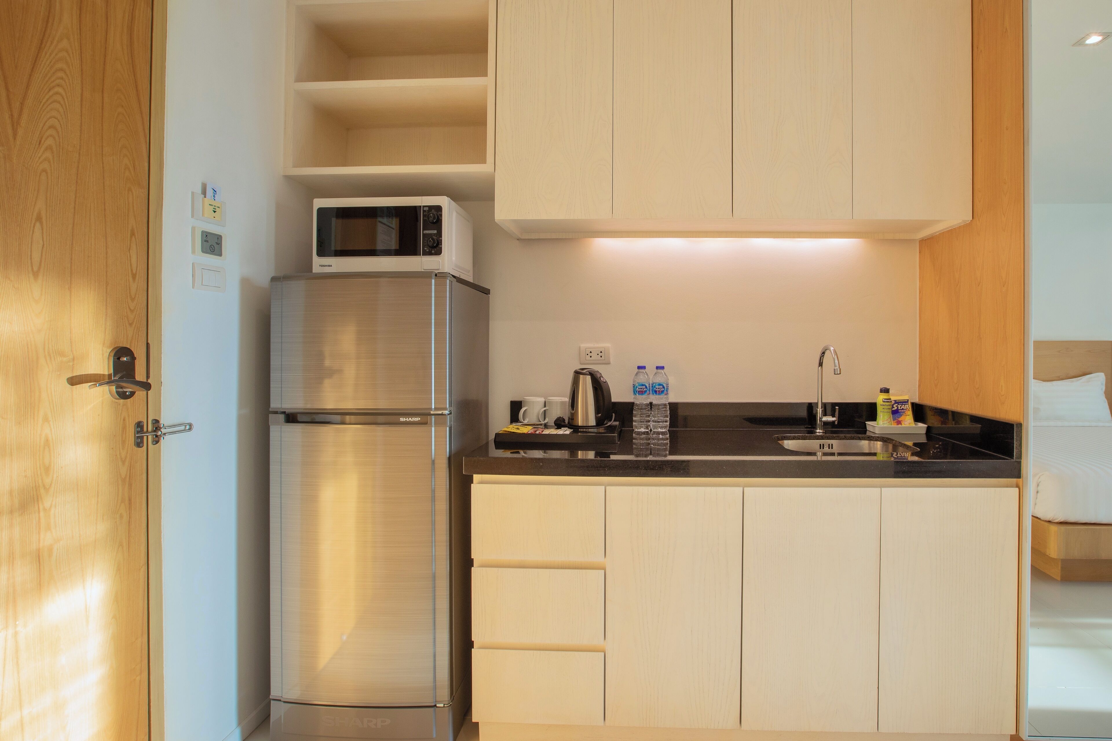 A compact kitchen with a microwave, refrigerator, and a sink.