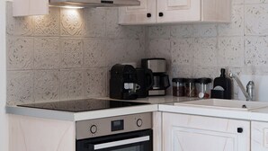 Eine Küche mit Herd, Backofen, Schränken und einer Kaffeemaschine.
