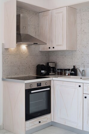Een keuken met een fornuis, oven, kasten en een koffiezetapparaat.