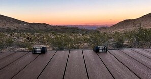 A wooden deck with two black objects, likely speakers, overlooking a hilly landscape with sparse vegetation. - Luxurious and Comfy Bell Tent in the Stunning Nevada Desert (Boulder City)