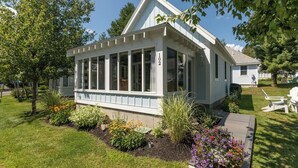 Eingeschossiges Haus mit überdachter Veranda, umgeben von einem gepflegten Garten mit verschiedenen Pflanzen und Blumen.
