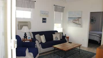 A living room with a sofa, a coffee table, and a painting of a beach scene.