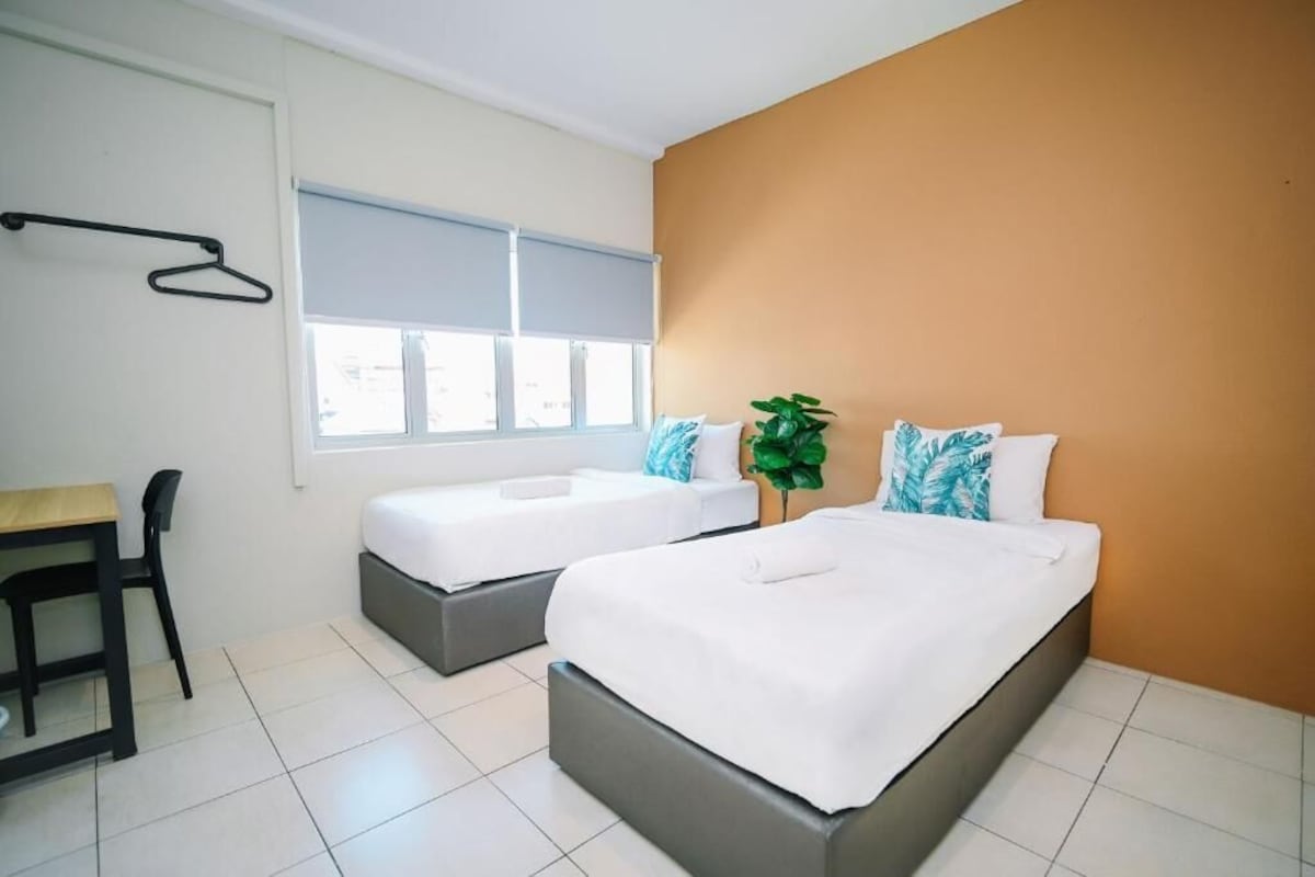 Una habitación de hotel moderna con dos camas, un escritorio y una ventana con persianas.