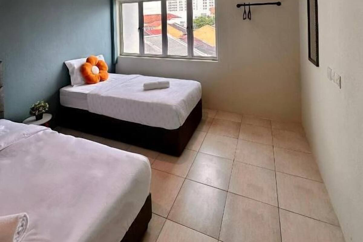Habitación de hotel moderna con dos camas, un ventanal con vistas a edificios y un aire acondicionado de pared.