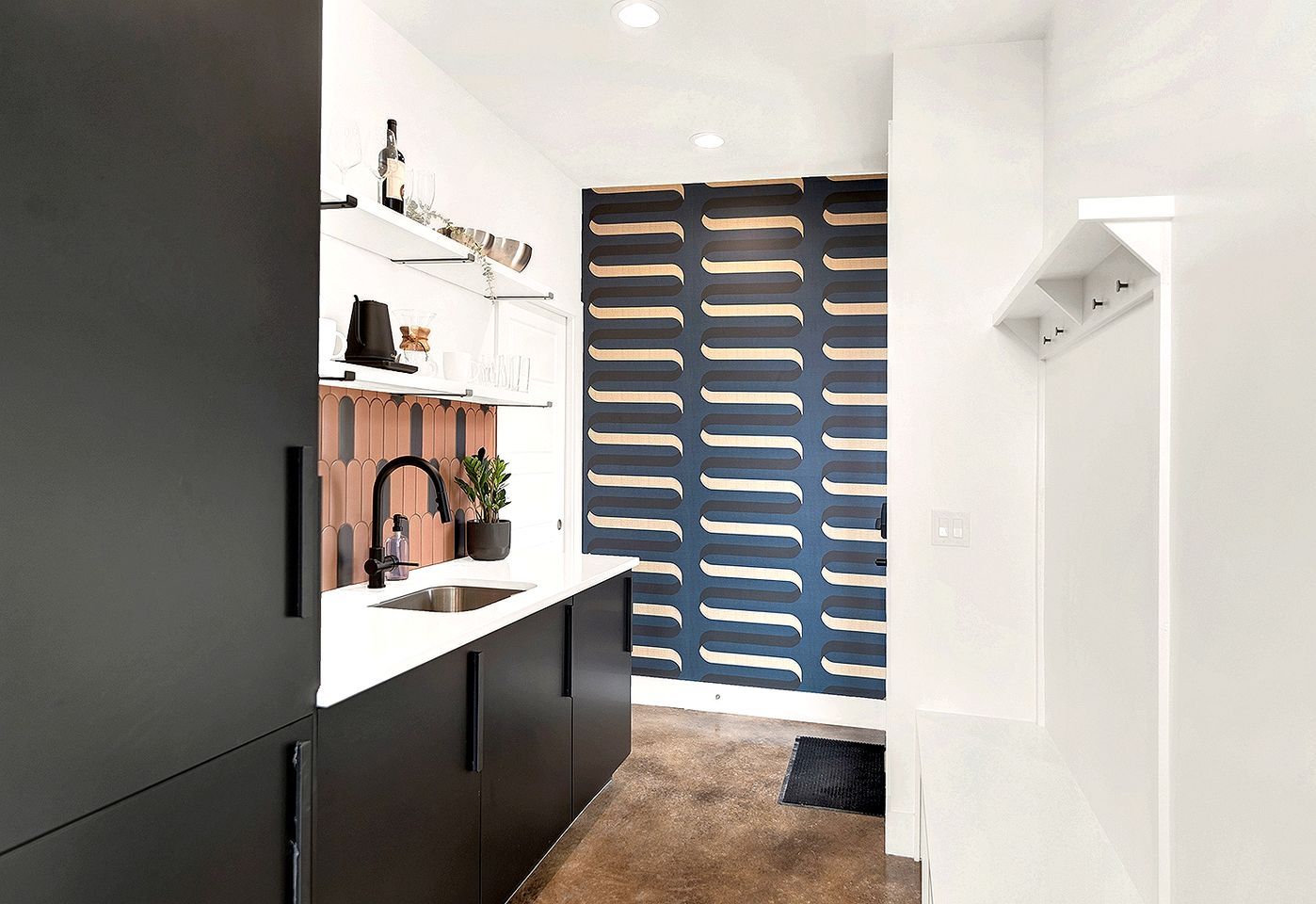 Cozinha moderna com bancada branca, armários pretos e painel decorativo na parede.