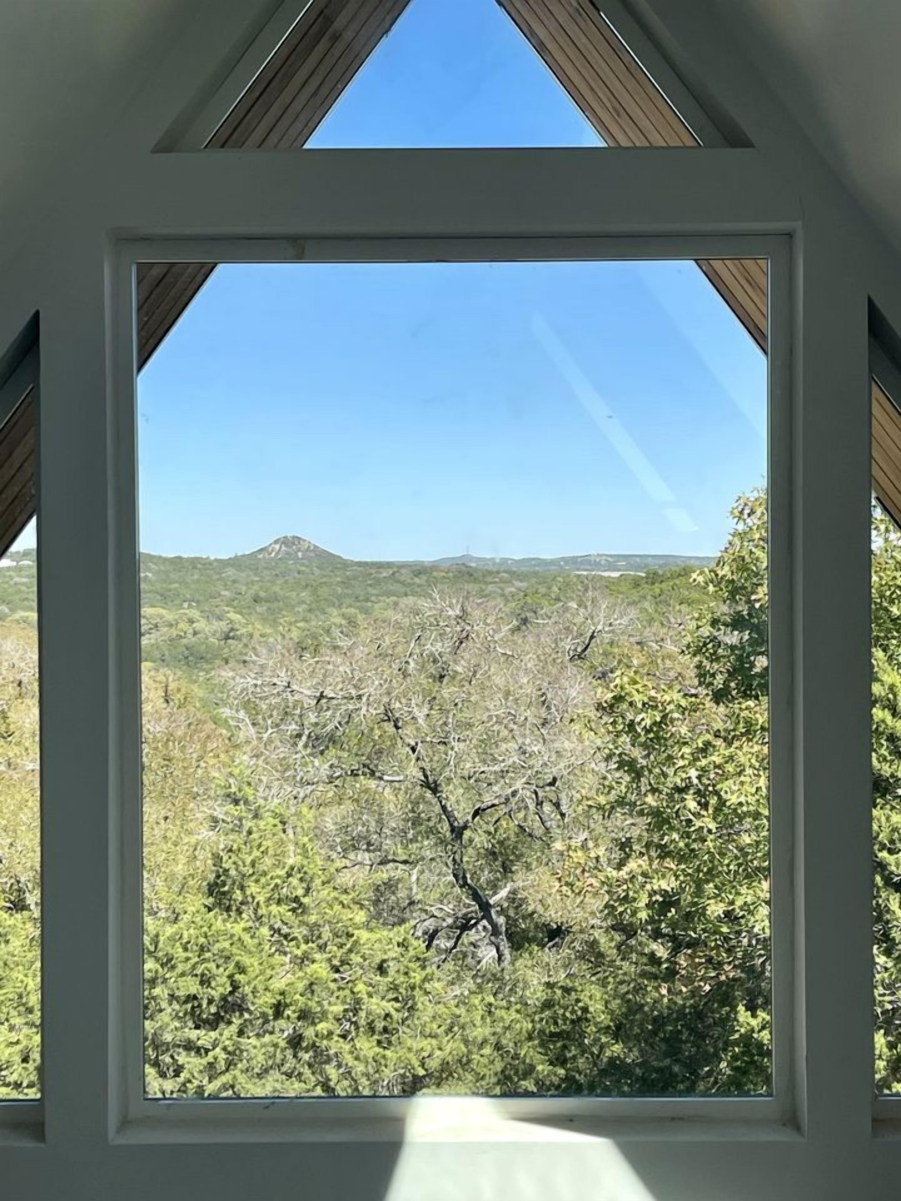 Habitació amb finestra gran que ofereix vistes a un paisatge de muntanya.