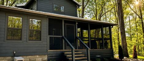 A two-story house with a covered porch and a stone foundation.