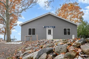 A two-story building with a gray exterior, a front door, and a sign that reads 'Cozy Home 2'. - Waterfront Cabin with BBQ, Picnic Space and Amazing Sunsets in Michigan (Au Gres)