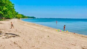 A beach with a sandy shore, trees, and a clear blue sky. - Waterfront Cabin with BBQ, Picnic Space and Amazing Sunsets in Michigan (Au Gres)