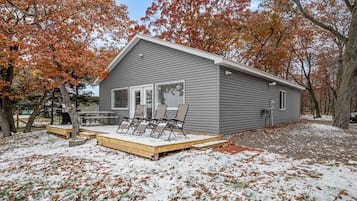 A single-story building with a covered porch, a grill, and outdoor seating.