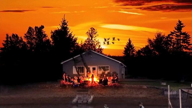 A house by a lake at sunset with a boat in the foreground. - Waterfront Cabin with BBQ, Picnic Space and Amazing Sunsets in Michigan (Au Gres)