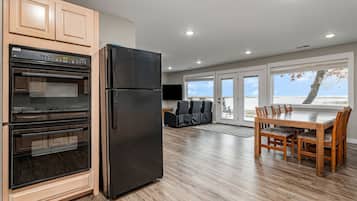 A modern kitchen with a black refrigerator, wooden cabinets, and a built-in oven.