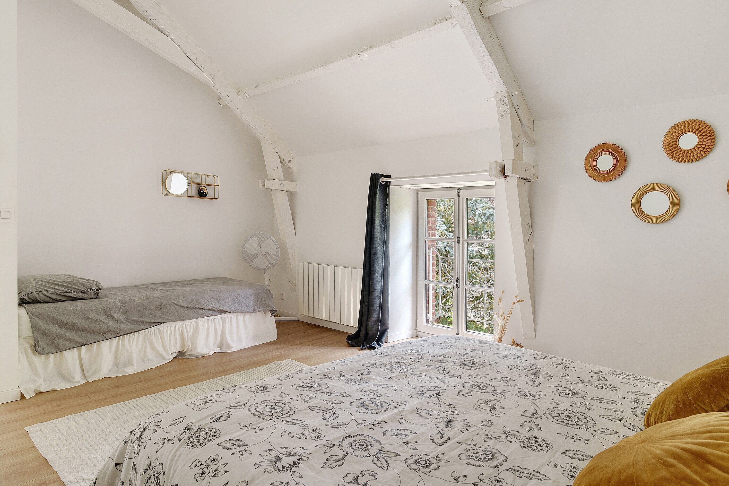 A bedroom with a bed, a smaller bed, a window with a view, and a radiator.
