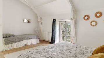A bedroom with a bed, a smaller bed, a window with a view, and a radiator.