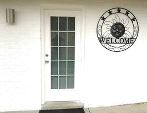 A white door with a window, a welcome sign, and a metal decorative piece. - Riverfront Cottage with Barbecue, Kayaks and Dock in Charlotte, North Carolina (Charlotte)