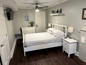 A bedroom with a bed, nightstands, a ceiling fan, a dresser, and a wall-mounted shelf.